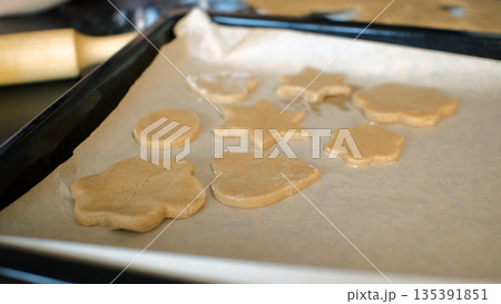 Raw ginger cookie pieces on a parchment-lined baking tray, homemade baking and cooking 135391851