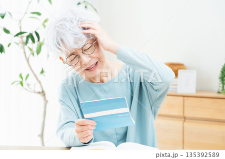 預金通帳を見て考えるシニア女性 135392589