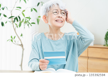 預金通帳を見て考えるシニア女性 135392594