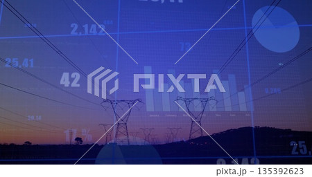 Stretching steel transmission towers and power lines across rural field at dusk, with data overlay 135392623