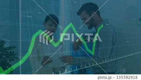 Reviewing translucent line chart and holding tablet, business-casual colleagues in office Reviewing translucent line chart and holding tablet, business-casual colleagues in office 135392918