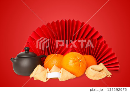 Festive scene with oranges, fortune cookies, and a teapot 135392976