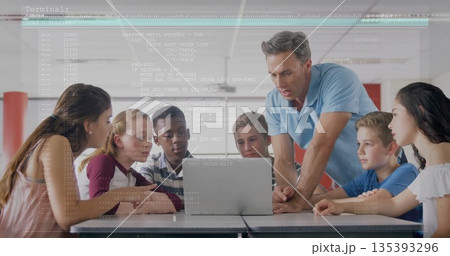 Guiding male instructor leaning over table instructing students at lab, with laptop code overlay 135393296