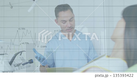 Consulting dentist in blue scrubs reviewing chart with patient in treatment room 135393422