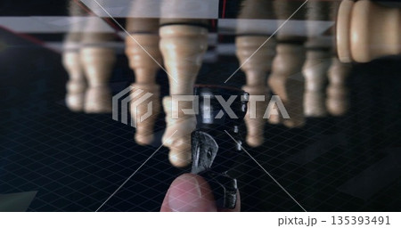 Grasping dark pawn between finger and thumb on glossy chessboard, with light pawn row behind Grasping dark pawn between finger and thumb on glossy chessboard, with light pawn row behind 135393491