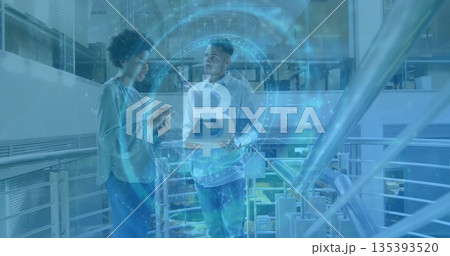 Colleagues holding smartphone and laptop discussing Bitcoin in office atrium, with Bitcoin hologram Colleagues holding smartphone and laptop discussing Bitcoin in office atrium, with Bitcoin hologram 135393520