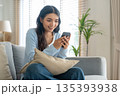 Smiling pretty young Asian woman sitting on cozy couch 135393938