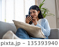 Smiling pretty young Asian woman sitting on cozy couch 135393940