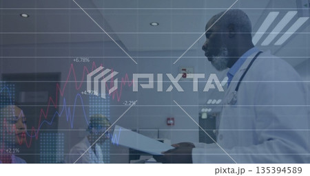 Mature male physician reviewing charts in hospital room, colleagues watching, digital overlay Mature male physician reviewing charts in hospital room, colleagues watching, digital overlay 135394589
