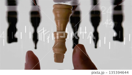 Holding upside-down wooden king piece with fingertips in studio, with reflections and data overlays 135394644