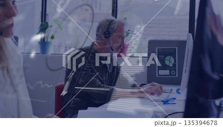 Typing office worker wearing headset and dark shirt using keyboard at modern office, with monitors Typing office worker wearing headset and dark shirt using keyboard at modern office, with monitors 135394678