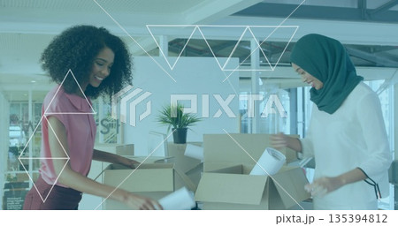Unpacking coworkers in blouse, headscarf sorting cardboard boxes, plans at office with potted plant Unpacking coworkers in blouse, headscarf sorting cardboard boxes, plans at office with potted plant 135394812