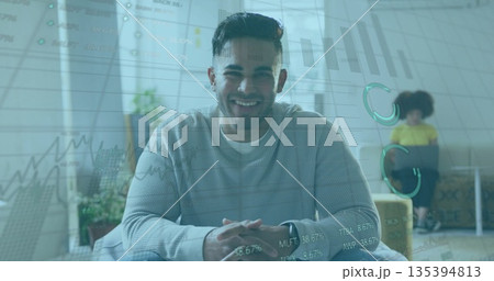 Smiling professional wearing sweater sitting on chair in home office, with financial charts overlay 135394813