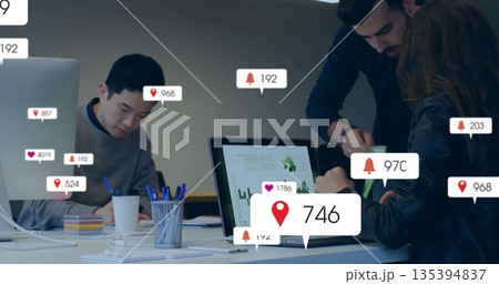 Collaborating coworkers typing at laptops and writing on notepads in boardroom, notification icons 135394837