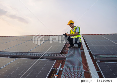 man in ayellow vest is inspecting  solar panel 135396041
