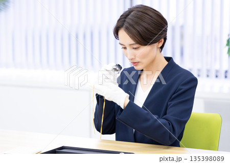 買取業者　窓口で査定をしている女性 135398089
