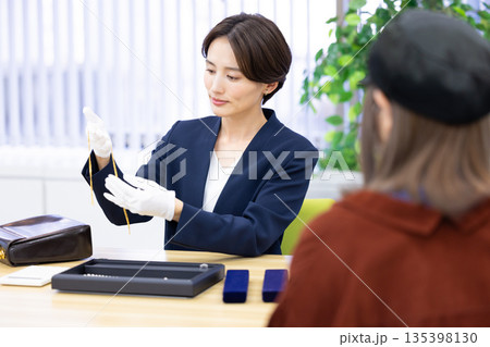 買取業者 窓口で査定をしている女性 買取業者 窓口で査定をしている女性 135398130