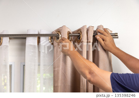 Handyman repairman hanging and fixing the curtain rod on the window 135398246