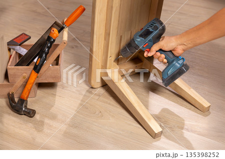 Handyman repair wooden bench in living room. 135398252