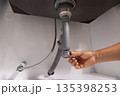 Plumber open trap to fixing drain clog under sink. 135398253