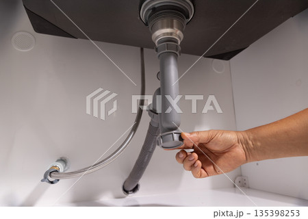 Plumber open trap to fixing drain clog under sink. 135398253