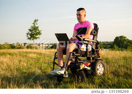 Modern lifestyle and accessibility concept with a wheelchair user working remotely outdoors. Modern lifestyle and accessibility concept with a wheelchair user working remotely outdoors. 135398269