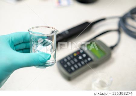 Woman hand in gloves adjusting a pH meter for water analysis Woman hand in gloves adjusting a pH meter for water analysis 135398274