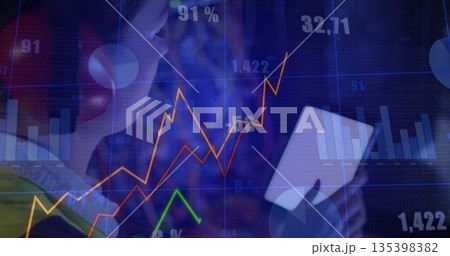 Analyzing woman wearing red headphones viewing white tablet in workspace, market charts, copy space 135398382