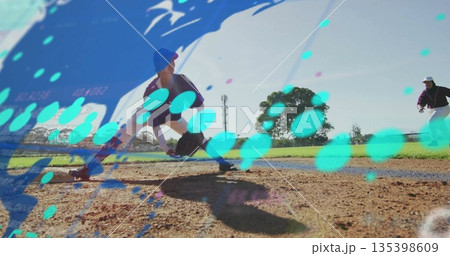 Sliding player in purple uniform crouching on base path at diamond, fielding ground ball with glove 135398609