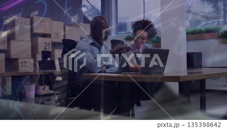 Gesticulating coworkers in office attire analyzing charts on laptop at conference table with plants 135398642