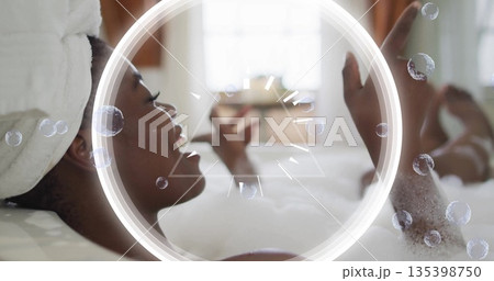 Relaxing woman raising arm in foamy bathtub by frosted window, with white towel turban, copy space Relaxing woman raising arm in foamy bathtub by frosted window, with white towel turban, copy space 135398750