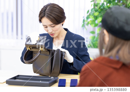 買取業者　窓口で査定をしている女性 135398880