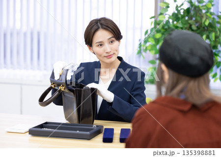 買取業者　窓口で査定をしている女性 135398881