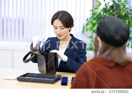 買取業者　窓口で査定をしている女性 135398882