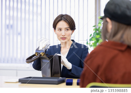 買取業者　窓口で査定をしている女性 135398885