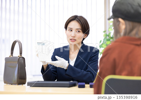 買取業者 窓口で査定をしている女性 買取業者 窓口で査定をしている女性 135398916
