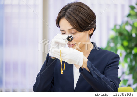 買取業者　窓口で査定をしている女性 135398935