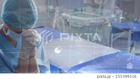 Standing surgeon in blue scrubs at operating table in surgical suite, with data overlay, copy space 135399316