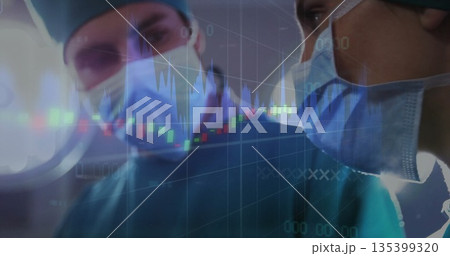 Leaning surgeons wearing green gowns operating microscope under OR lights, with stock chart overlay 135399320