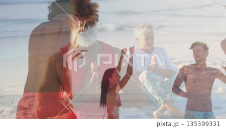 Dancing trio in red athletic gear and pink bikini energizing sandy beach, with seated meditators 135399331