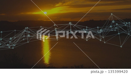 Glowing digital network overlay spanning lakeshore at sunset, showing nodes and connecting lines 135399420