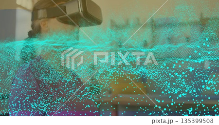 Woman wearing VR headset exploring data field in softly lit room with turquoise overlay, copy space 135399508