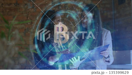 Examining two women in blazers reviewing folder in modern office, with holographic Bitcoin overlay Examining two women in blazers reviewing folder in modern office, with holographic Bitcoin overlay 135399629