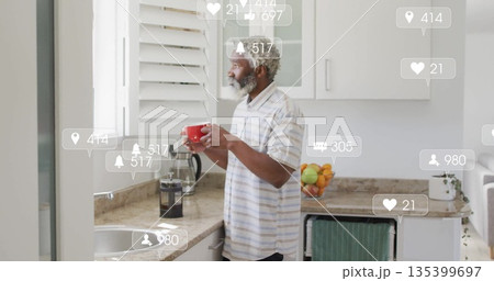 Holding red mug, man in striped shirt watching digital notification icons in kitchen, copy space Holding red mug, man in striped shirt watching digital notification icons in kitchen, copy space 135399697