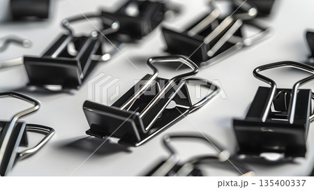 白背景に散らばる黒いダブルクリップ 白背景に散らばる黒いダブルクリップ 135400337