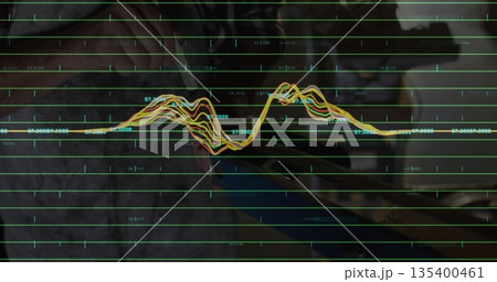 Data analyst analyzing waveform on tablet screen at home office desk, with stylus and laptop 135400461