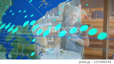 Holding smartphone, bearded man eating from salad bowl at café table, with digital code overlay 135400544