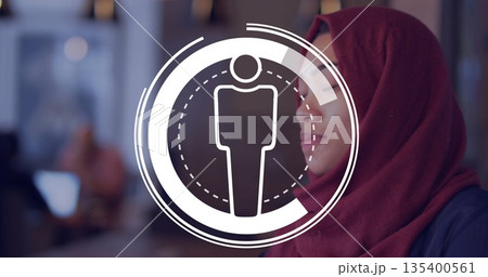 Woman wearing red hijab and blazer viewing profile overlay in office lounge, with desks, copy space Woman wearing red hijab and blazer viewing profile overlay in office lounge, with desks, copy space 135400561
