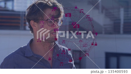 Standing male wearing eyeglasses and blue shirt on rooftop terrace with magenta network icons 135400593