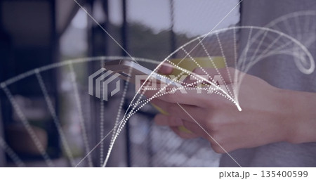 Holding silver smartphone while displaying white dotted arc on balcony railing overlooking greenery 135400599